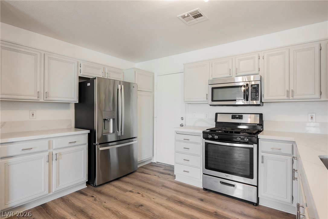 112 Iridescent Street Henderson, NV 89012 - Photo 10 of 24 A clean, functional kitchen featuring pristine white cabinetry and essential stainless steel appliances.