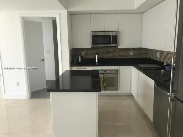 a kitchen with kitchen island sink and refrigerator