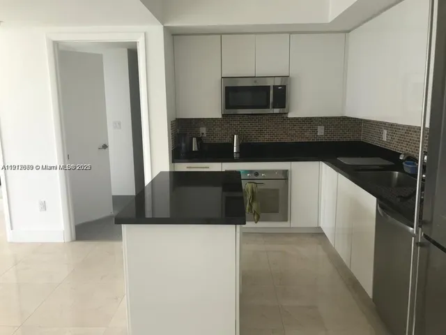a kitchen with kitchen island sink and refrigerator