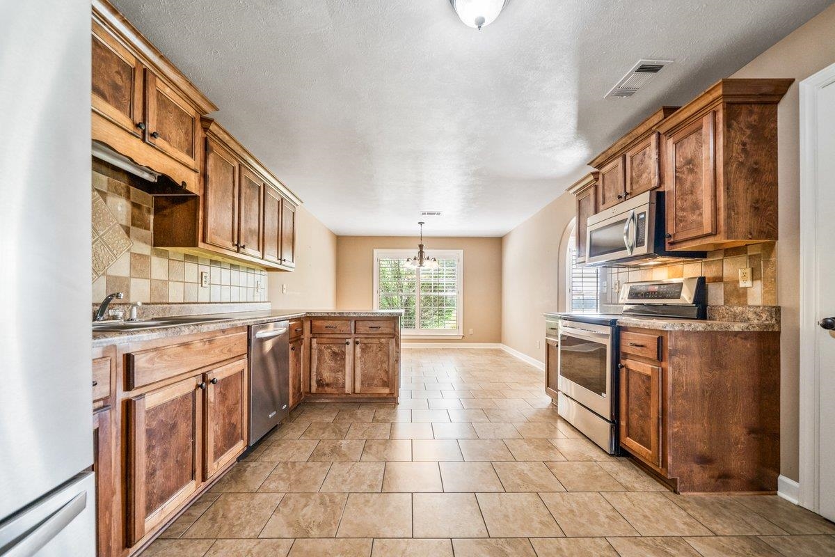 583 Rosemark Road Atoka, TN 38004 - Photo 10 of 25 a large kitchen with stainless steel appliances granite countertop a stove a sink and a refrigerator