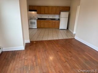 390 Main Street, Unit 3 Beacon, NY 12508 - Photo 1 of 8 Kitchen with baseboards, white appliances, light wood-style floors, and brown cabinets