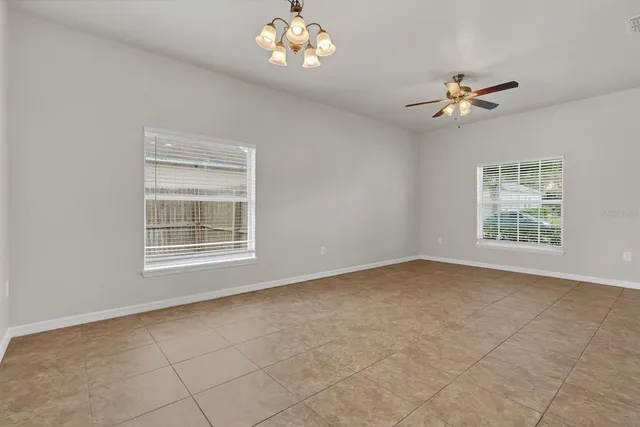 en empty room with windows and ceiling fan