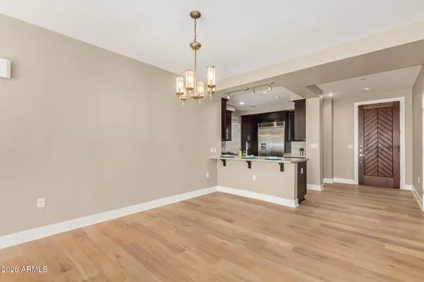 a view of a hallway with wooden floor and a kitchen