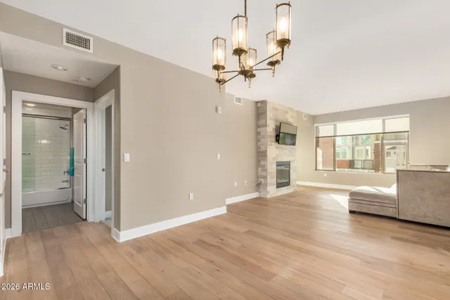 a view of an empty room with a window and wooden floor
