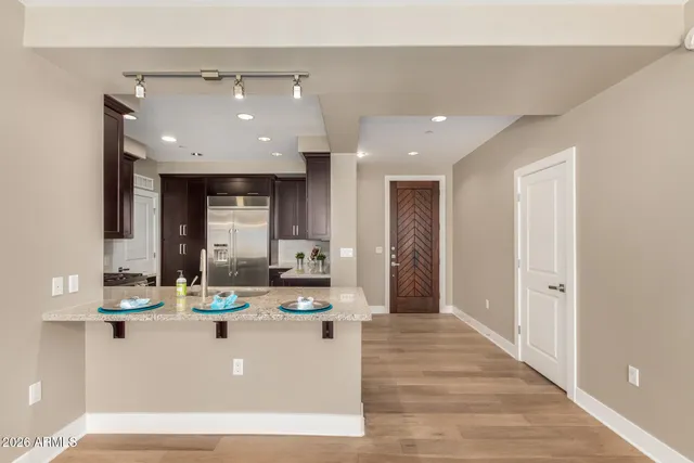a living room with kitchen island stainless steel appliances a sink cabinets and wooden floor