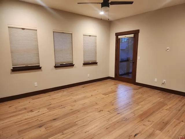 an empty room with wooden floor and windows