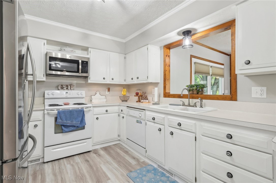 5418 River Road Madison, OH 44057 - Photo 31 of 43 Kitchen with light wood-type flooring, white cabinets, sink, a textured ceiling, and stainless steel appliances