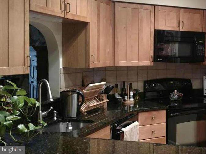 11286 Harbor Court, Unit 11286 Reston, VA 20191 - Photo 16 of 27 a kitchen with granite countertop a stove a microwave a sink and cabinets