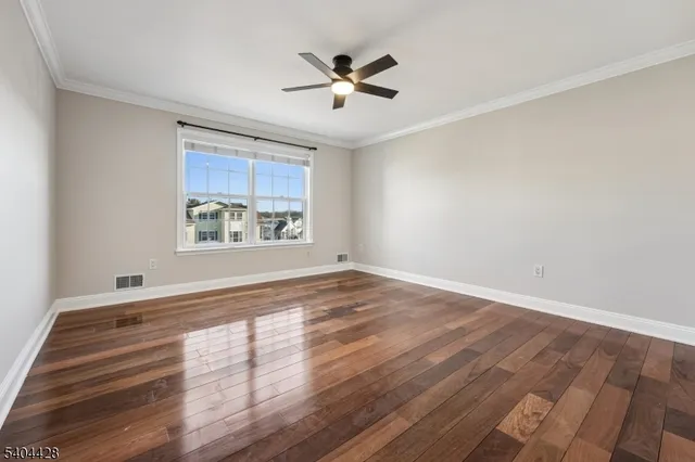 an empty room with wooden floor ceiling fan and windows