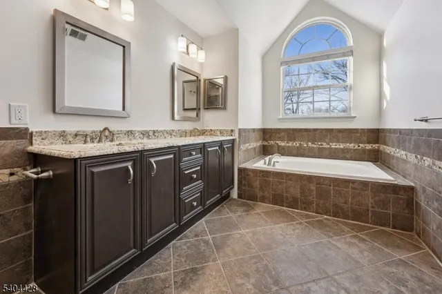 a spacious bathroom with a tub a sink and mirror