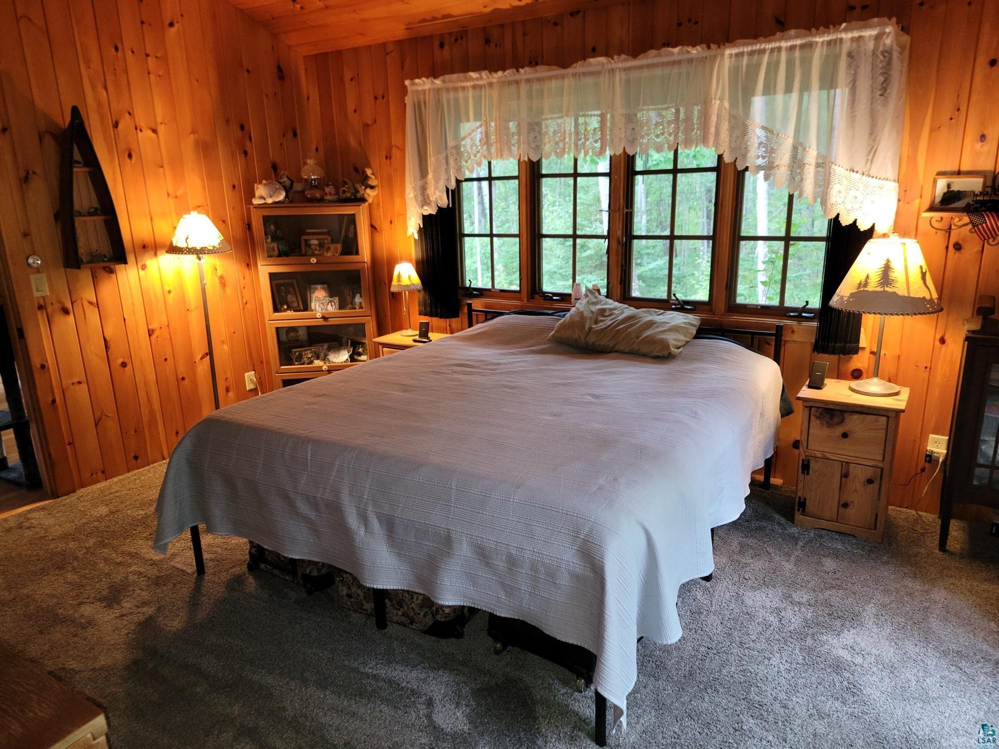 181 Linnell Road Grand Marais, MN 55604 - Photo 45 of 77 Wood-paneled walls and ceiling, multi-pane window, carpet flooring, and built-in shelving