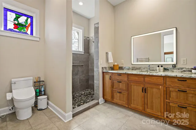 a spacious bathroom with a granite countertop sink a toilet and a shower