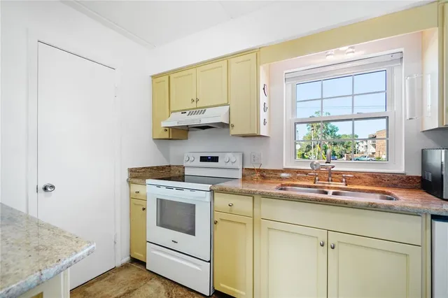 a kitchen with stainless steel appliances granite countertop white cabinets and a window