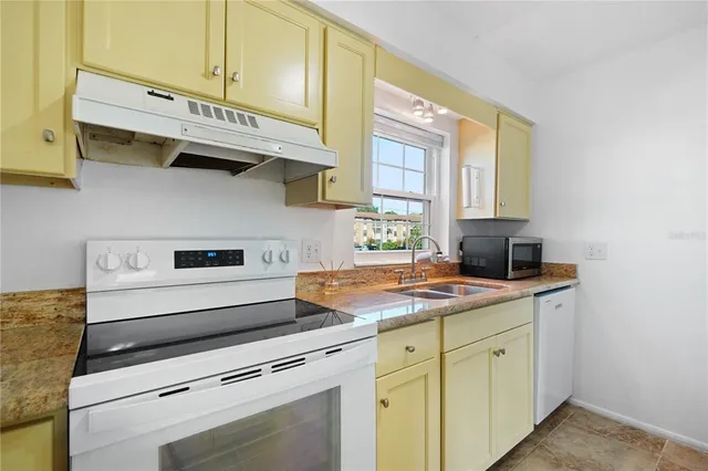 a kitchen with stainless steel appliances granite countertop a sink window and cabinets