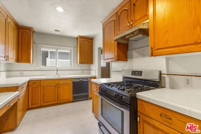 a kitchen with stainless steel appliances a sink a stove and cabinets