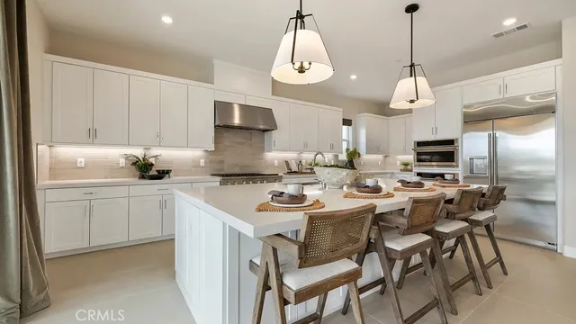 a kitchen with stainless steel appliances a dining table chairs and sink