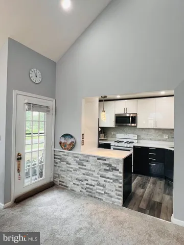 a kitchen with stainless steel appliances kitchen island granite countertop a stove top oven a sink a counter space and cabinets