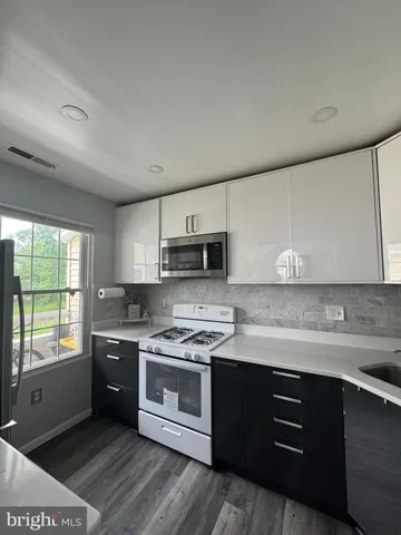 a kitchen with stainless steel appliances granite countertop a sink a stove a refrigerator cabinets and a window