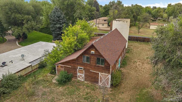 a view of a barn in the yard with large trees