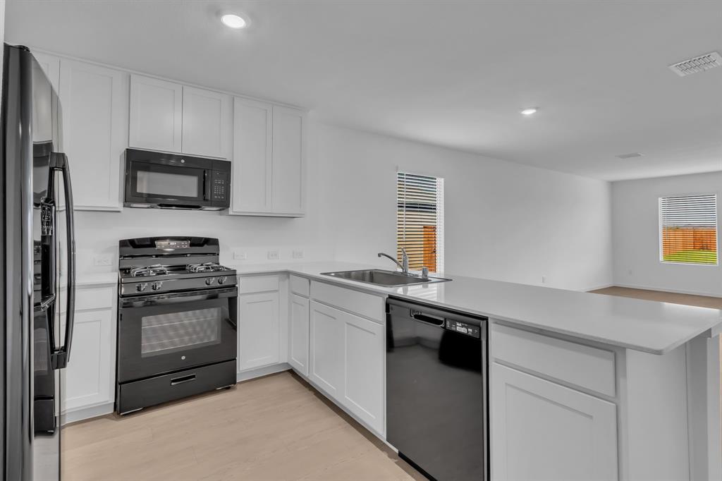 11325 Rodeo Drive Providence Village, TX 76227 - Photo 13 of 40 a kitchen with granite countertop a sink and stainless steel appliances