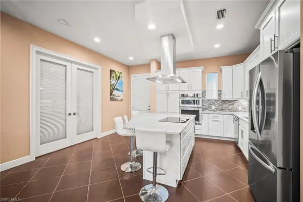 a kitchen with stainless steel appliances a refrigerator a sink dishwasher a stove and white cabinets with wooden floor