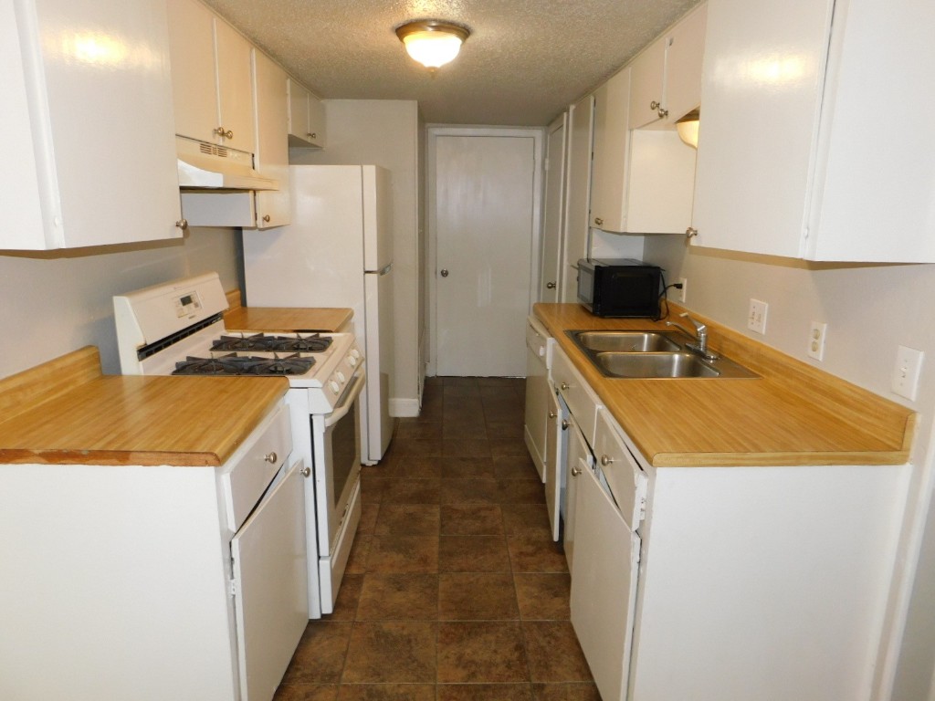 1007 Windy Trail, Unit A Austin, TX 78758 - Photo 1 of 10 Kitchen featuring white gas stove, a sink, black microwave, under cabinet range hood, and light countertops
