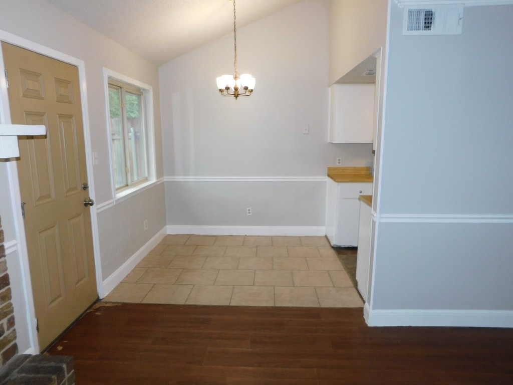 1007 Windy Trail, Unit A Austin, TX 78758 - Photo 3 of 10 Unfurnished dining area with vaulted ceiling, a chandelier, light wood-type flooring, and baseboards