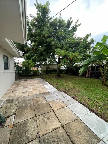 a view of a yard with plants and a bench