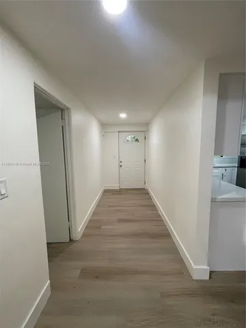 a view of a hallway with wooden floor and a living room