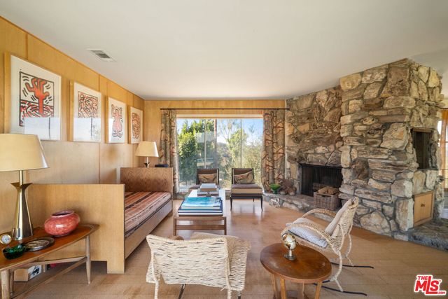 a living room with furniture a fireplace and a floor to ceiling window