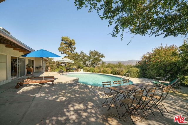 a view of a swimming pool with a patio and a yard