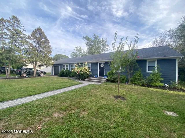 a view of house in front of a big yard with plants and large trees