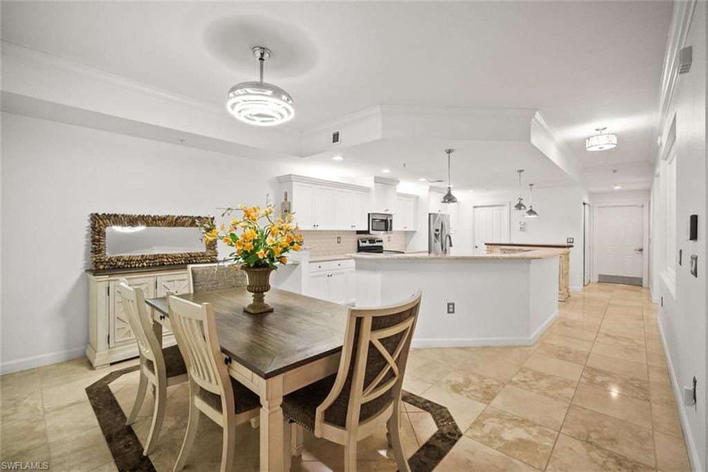 8701 Piazza Del Lago Circle, Unit 101 Estero, FL 33928 - Photo 15 of 50 a kitchen with stainless steel appliances kitchen island granite countertop a dining table chairs and white cabinets