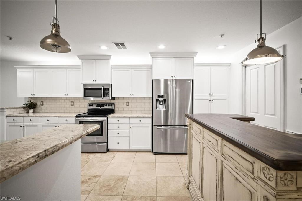 8701 Piazza Del Lago Circle, Unit 101 Estero, FL 33928 - Photo 18 of 50 a kitchen with stainless steel appliances granite countertop a refrigerator a stove a sink and a refrigerator