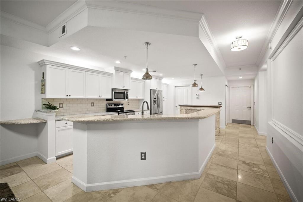 8701 Piazza Del Lago Circle, Unit 101 Estero, FL 33928 - Photo 24 of 50 a kitchen with kitchen island a sink stainless steel appliances and cabinets