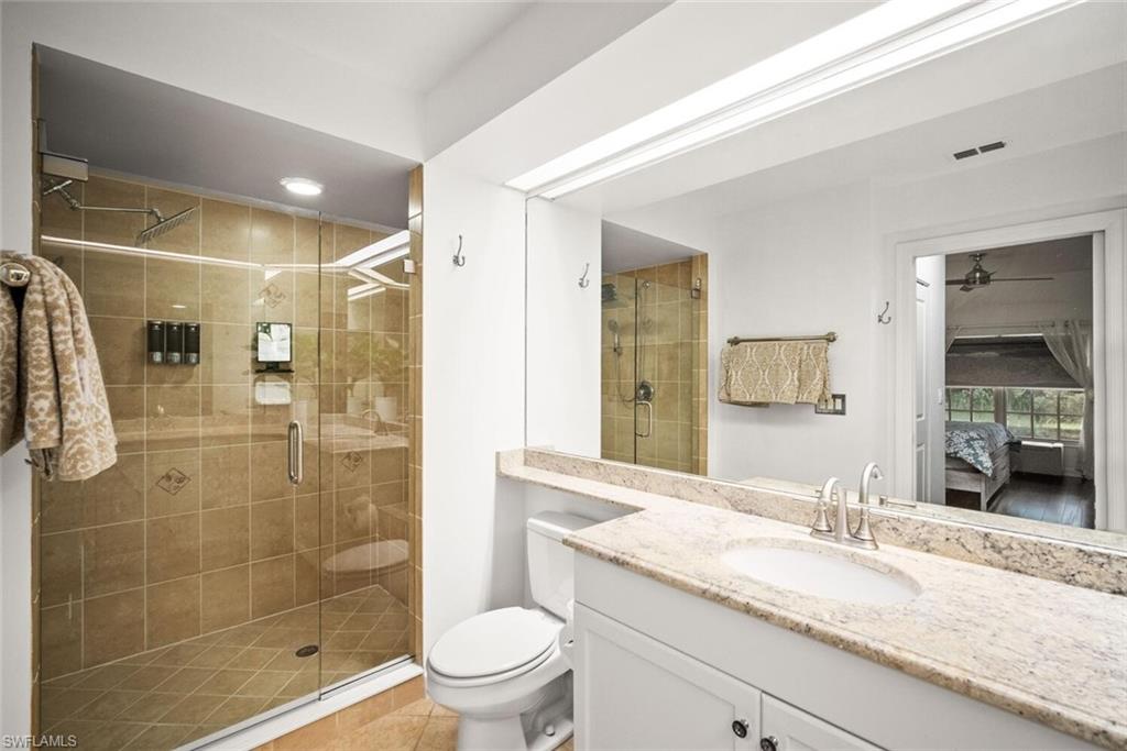 8701 Piazza Del Lago Circle, Unit 101 Estero, FL 33928 - Photo 30 of 50 a bathroom with a granite countertop sink a toilet a mirror and shower