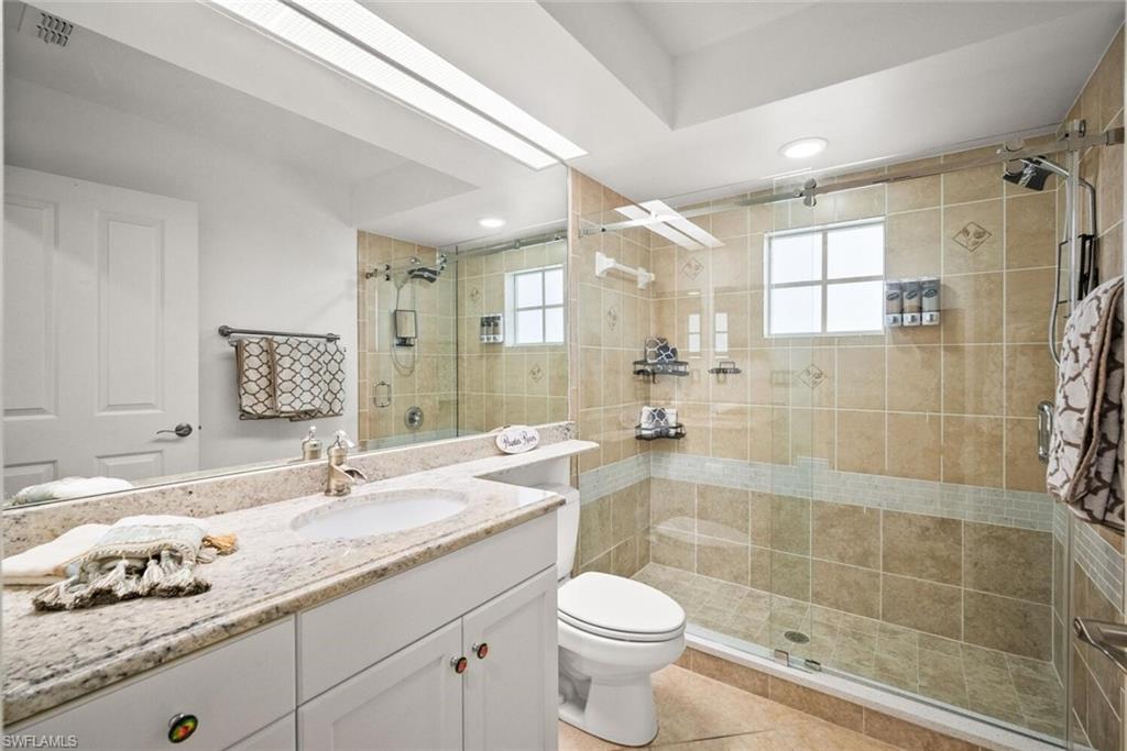 8701 Piazza Del Lago Circle, Unit 101 Estero, FL 33928 - Photo 35 of 50 a bathroom with a granite countertop sink a toilet a mirror and shower