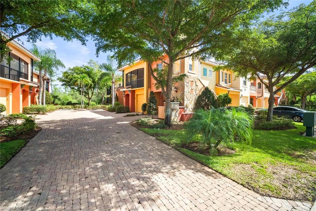 8701 Piazza Del Lago Circle, Unit 101 Estero, FL 33928 - Photo 10 of 50 a view of a white house next to a yard with big trees