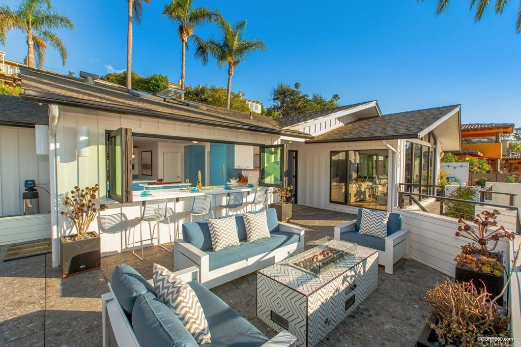 1237 Muirlands Vista Way La Jolla, CA 92037 - Photo 9 of 25 a view of a patio with couches table and chairs with potted plants and palm trees