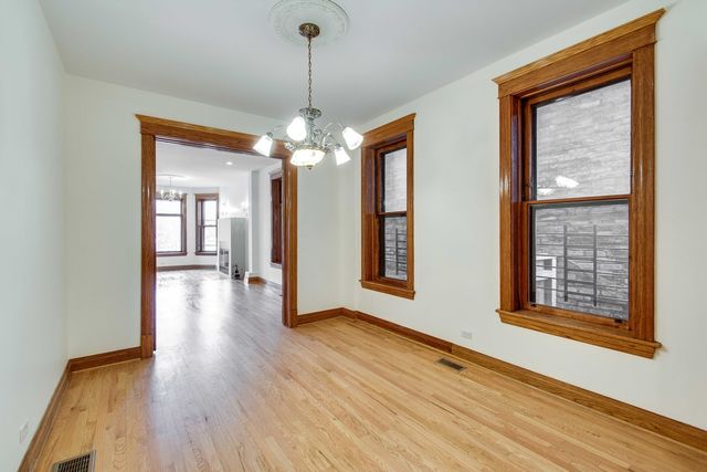 a view of a room with wooden floor chandelier and windows