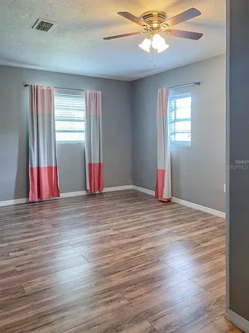 an empty room with wooden floor and windows