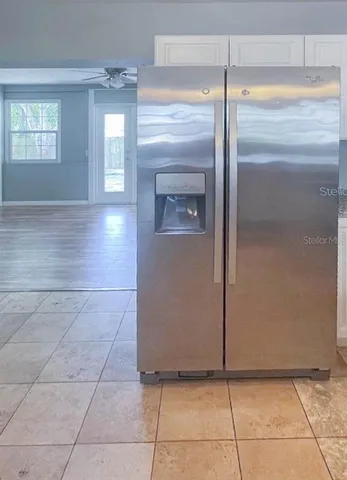 a view of a refrigerator in kitchen and an empty room