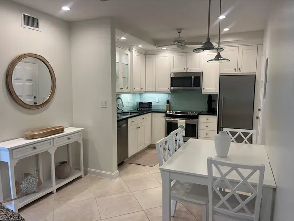 a kitchen with stainless steel appliances granite countertop a stove top oven a sink dishwasher a dining table and chairs with wooden floor