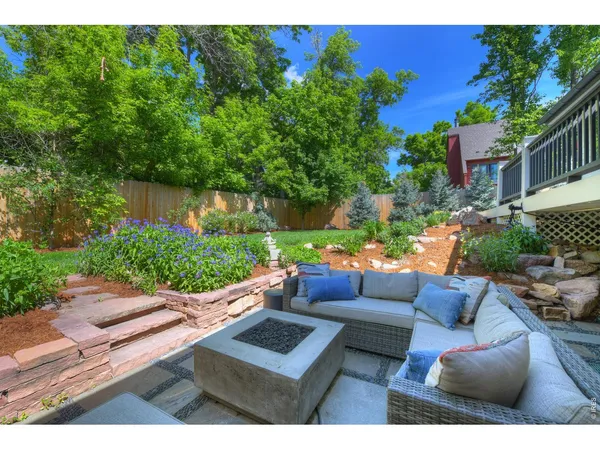 a view of a patio with couches and a fire pit and wooden fence