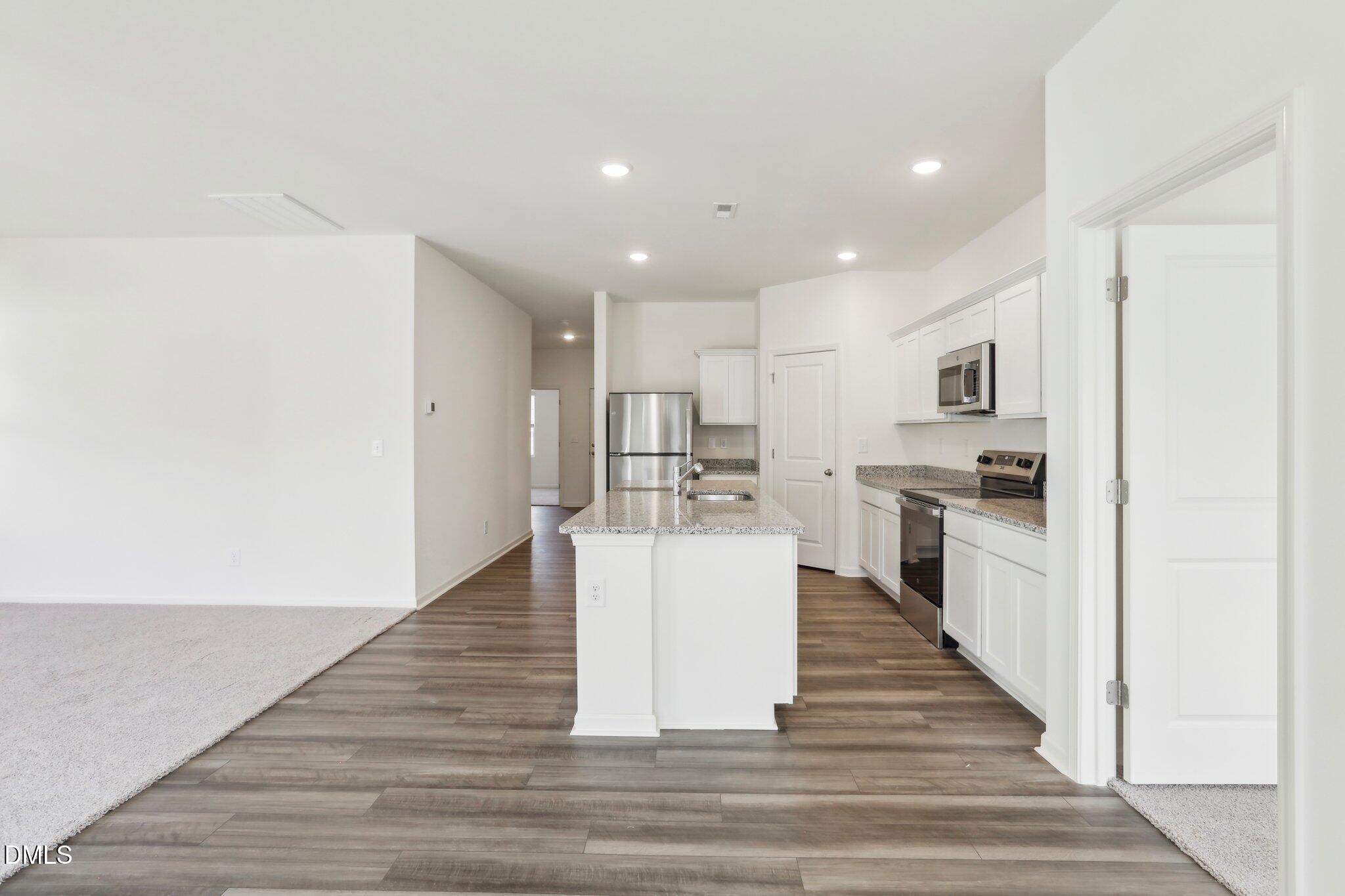 2573 Quarry Road Rolesville, NC 27571 - Photo 18 of 44 a large white kitchen with kitchen island a sink a stove and a refrigerator