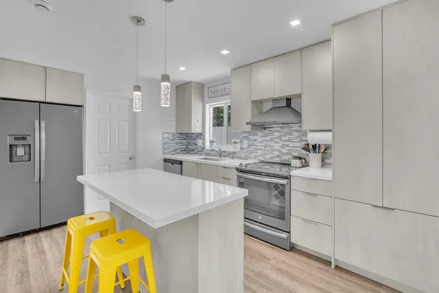 a kitchen with kitchen island a stove a sink and a refrigerator