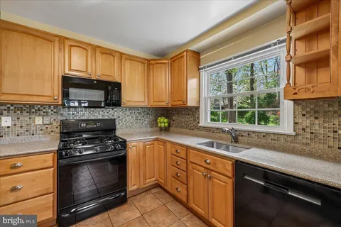 a kitchen with stainless steel appliances granite countertop a stove top oven a sink dishwasher a dining table and chairs with wooden floor