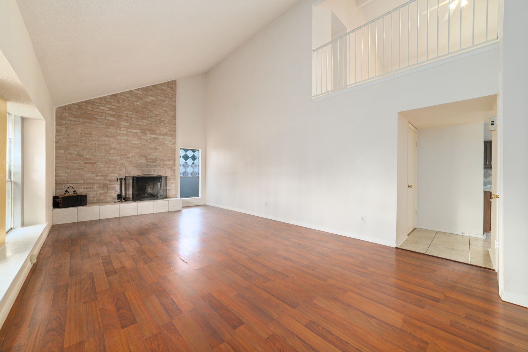 25402 Mill Pond Lane Spring, TX 77373 - Photo 11 of 24 This spacious living area features high ceilings, a brick fireplace, and warm hardwood floors. A large window lets in natural light, and there's an open loft area above.