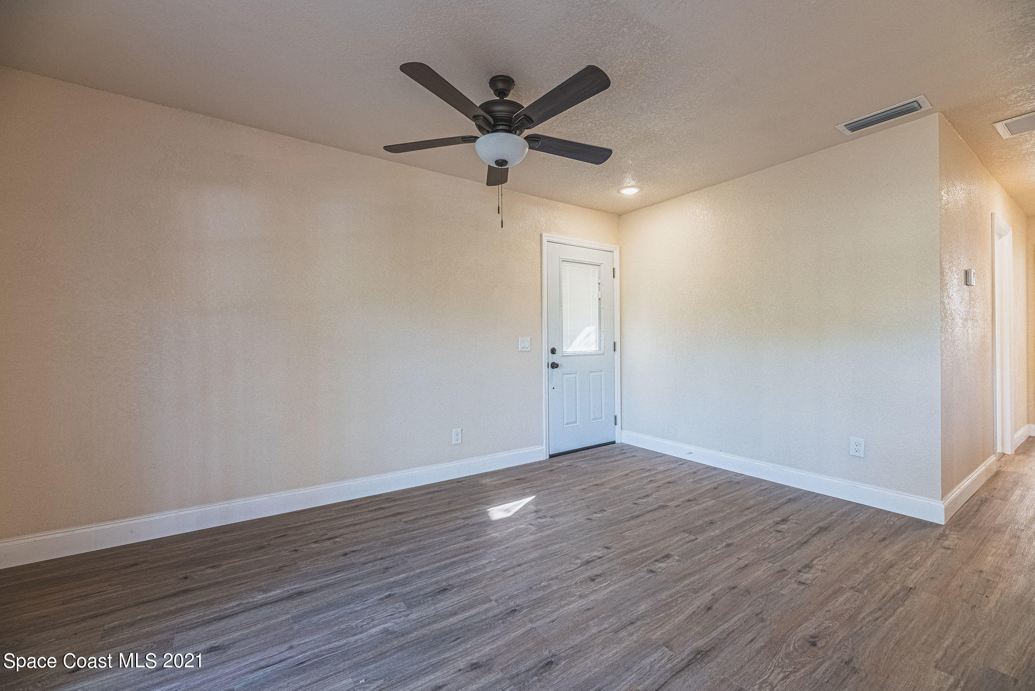 765 Garvey Road Palm Bay, FL 32908 - Photo 13 of 81 a view of an empty room with wooden floor and a ceiling fan