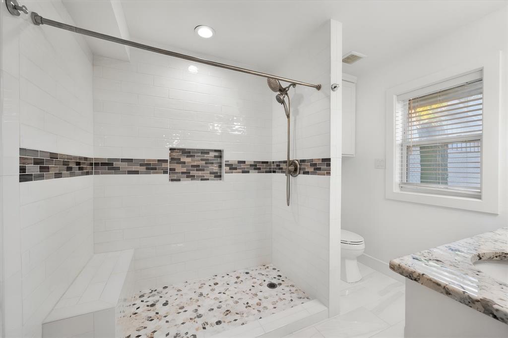 917 Goodwyn Road Italy, TX 76651 - Photo 10 of 40 Walk-in shower with pebble tile flooring, built-in bench, and decorative mosaic tile band